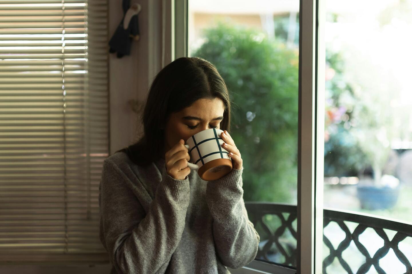 Femme buvant une tasse près d'une fenêtre - hypersensibilité au travail